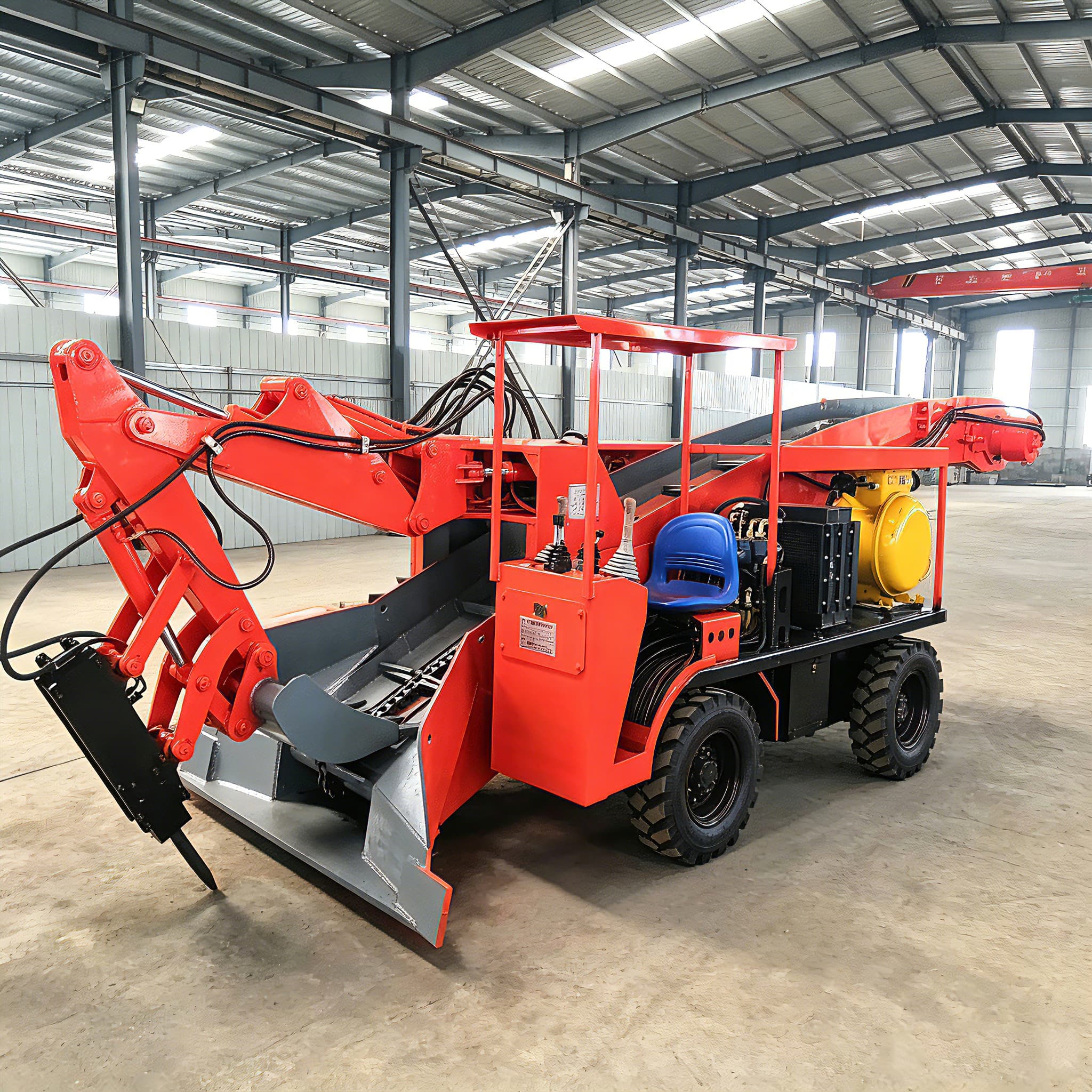 Red wheeled mucking loader photographed in a workshop